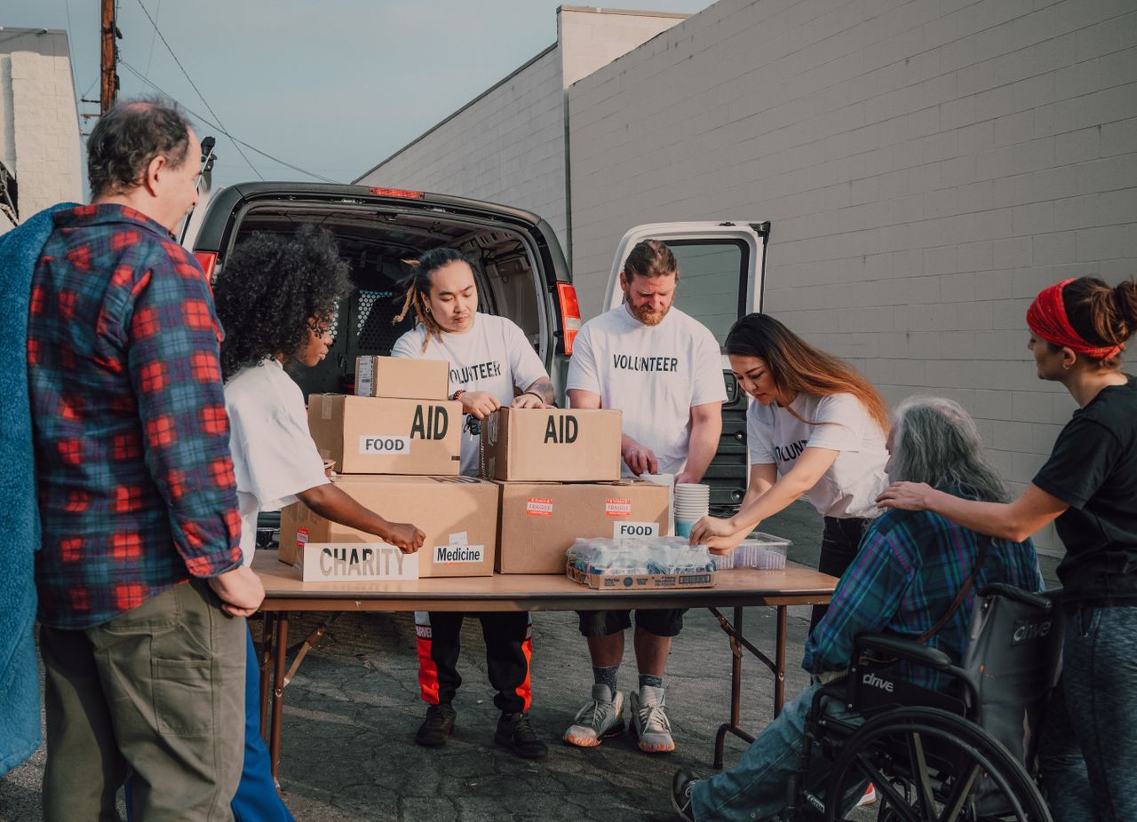 Group of diverse volunteers organizing aid packages outdoors for a charity event.