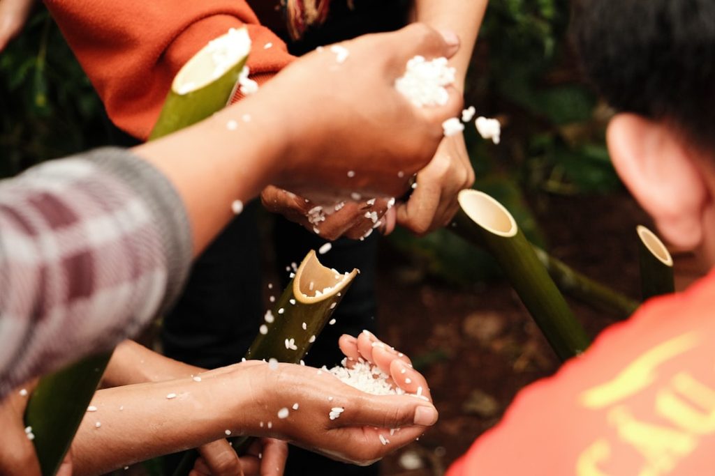 hands-holding-white-grains-pouring-from-bamboo-tubes-rgjtknoypzs
